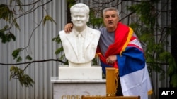 A man poses for a photograph next to the grave of late Yugoslav President Slobodan Milosevic in the town of Pozarevac, March 11, 2016