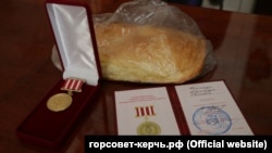 Хлеб и юбилейные медали, которые депутаты дарили керчанам, пережившим блокаду Ленинграда 