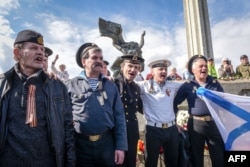 Men dressed in military uniforms gather at the Victory Monument as members of the Russian minority mark the end of World War II and commemorate the Soviet victory over Nazi Germany in Riga on May 9, 2017.