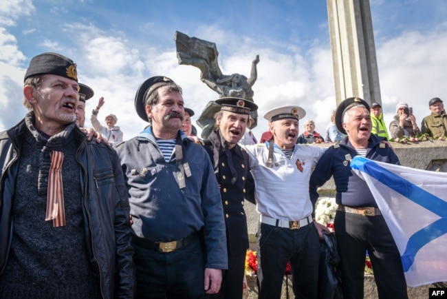 Burra të veshur me uniforma ushtarake të mbledhur para Monumentit të Fitores, teksa minoriteti rus shënon përfundimin e Luftës së Dytë Botërore dhe Fitoren e Bashkimit Sovjetik ndaj Gjermanisë Naziste. Riga, 9 maj 2017.