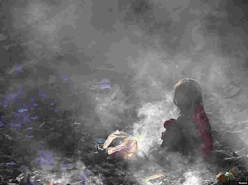 Avganistanska devojčica sedi na zapaljenom smetlištu u Kabulu (Reuters/Mohammad Ismail)