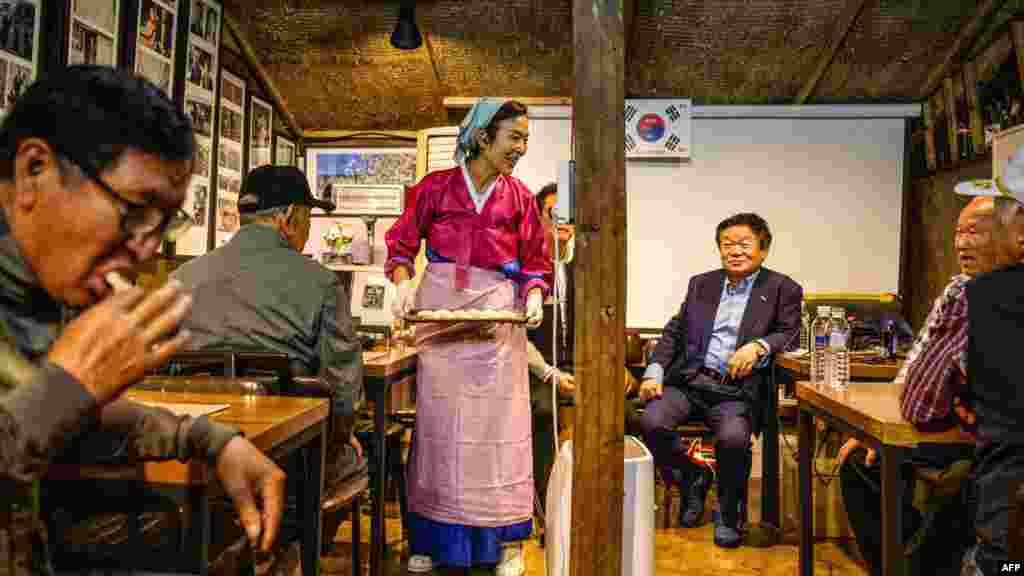 Son Yun-kyung (áll) észak-koreai stílusú mandut (nemzeti étel) szolgál fel idős embereknek és észak-koreai menekülteknek, akik összegyűltek, hogy régi koreai balladákat énekeljenek a Chuseok ünnep alkalmával a Gyodong-szigeten, körülbelül 2,3 kilométerre Észak-Koreától