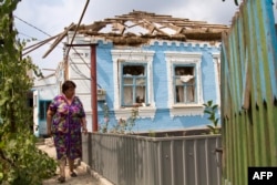 A resident walks in front of her house which was destroyed by shelling by pro-Russian separatists in the village of Sartana, near Mariupol, on August 17.