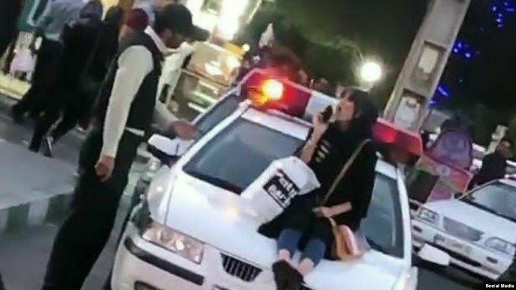 Photo published on social media shows a young woman sitting on a police car in Iran. Undated