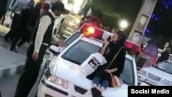 Photo published on social media shows a young woman sitting on a police car in Iran. Undated