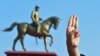 Un protestatar ridică salutul cu trei degete în timpul unei demonstrații la monumentul generalului Aung San (L), răposatul tată al lui Suu Kyi din Naypyitaw.(Fotografie de STR / AFP)