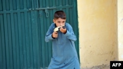 A boy holds a toy gun near the closed house of Rimsha, a Christian girl who has been arrested on blasphemy charges, in a slum area of Islamabad.