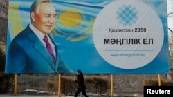 Женщина проходит мимо билборда с изображением президента Нурсултана Назарбаева. Алматы,16 февраля 2015 года.