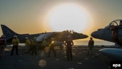 АҚШнинг AV-8B Harrier ҳарбий самолёти кема бортидан ҳавога кўтарилишга ҳозирлик кўрмоқда.