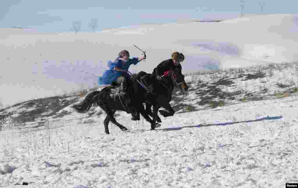 A Kazakh woman whips a male contestant as she defends herself during a Kyz Kuu (catch the girl) riding game at a winter festival in Yining, in China's Xinjiang Autonomous Region. (Reuters/China Daily)