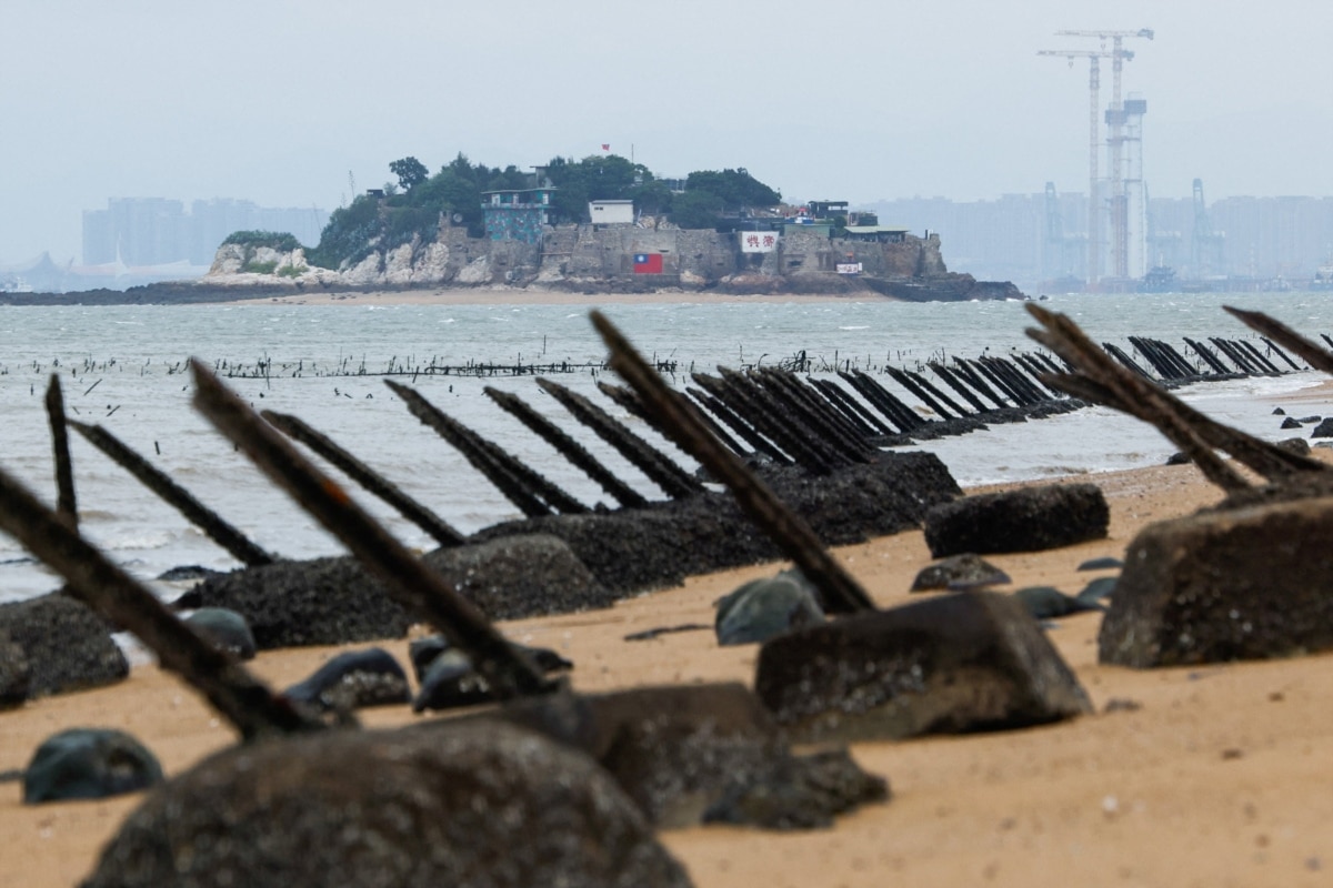 The small island of Shiyu, part of the Kinmen archipelago administered by the Republic of China (Taiwan), sits in a bay just off the coast of mainland China. The Chinese city of Xiamen is visible in the background, with the fortified PRC coastline in the foreground.