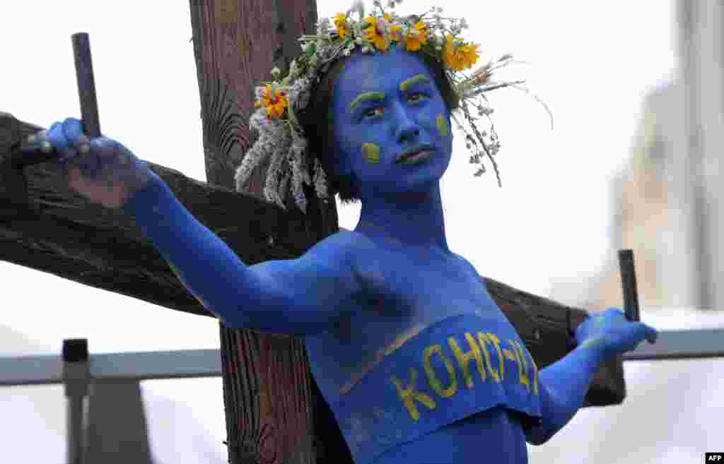 A woman symbolizing the Ukrainian Constitution is "crucified" during a performance called by Guy Fawkes activists in front of the Constitutional Court building in Kyiv. The activists are calling on Ukrainians to take action to defend the constitution. (AFP)