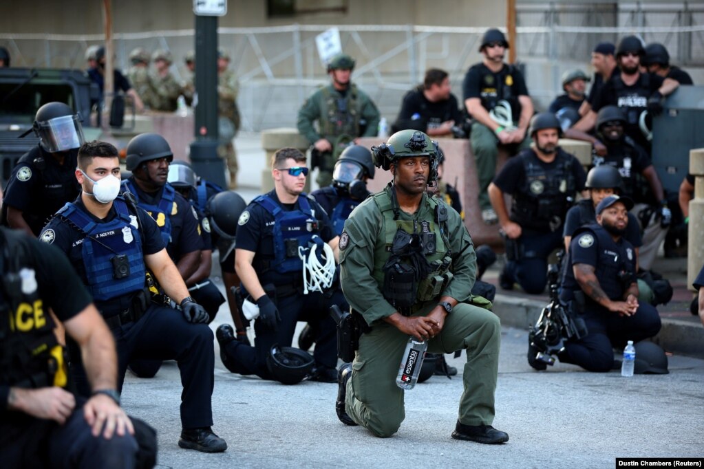 Zyrtarët policorë ulen në gjunjë gjatë një proteste në Xhorxhia, pas vdekjes së afrikano-amerikanit Floyd.