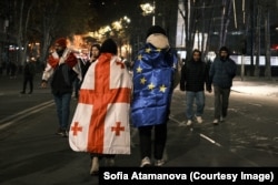 Protestatari înfășurați în steagurile Georgiei și UE la Tbilisi, la una din manifestațiile de la începutul lunii decembrie.