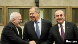 Russian Foreign Minister Sergei Lavrov, Turkish Foreign Minister Mevlut Cavusoglu and Iranian Foreign Minister Mohammad Javad Zarif shake hands as they attend a news conference after talks on forming a constitutional committee in Syria, at the United Nati