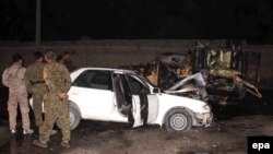 Afghan security officials inspect the site of a bomb blast that apparently targeted a police vehicle, in Lashkargah, Helmand Province, on February 28.