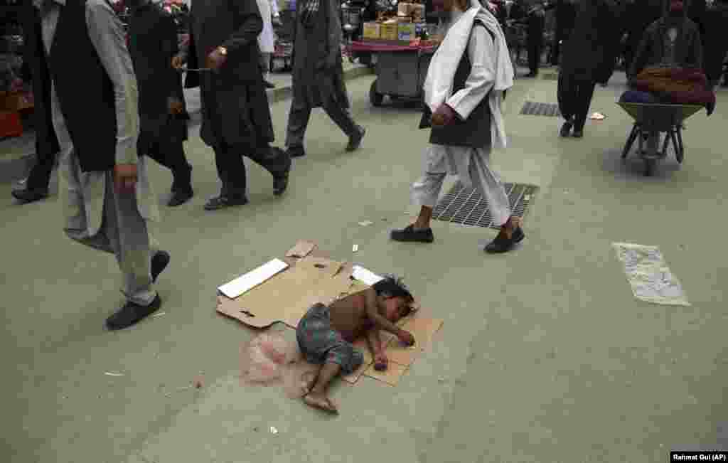 Kabul. Mukaddes Remezan aýynyň öňüsyrasynda ýerde sadaka garaşyp uklap ýatan çaga. (AP/Rahmat Gul)