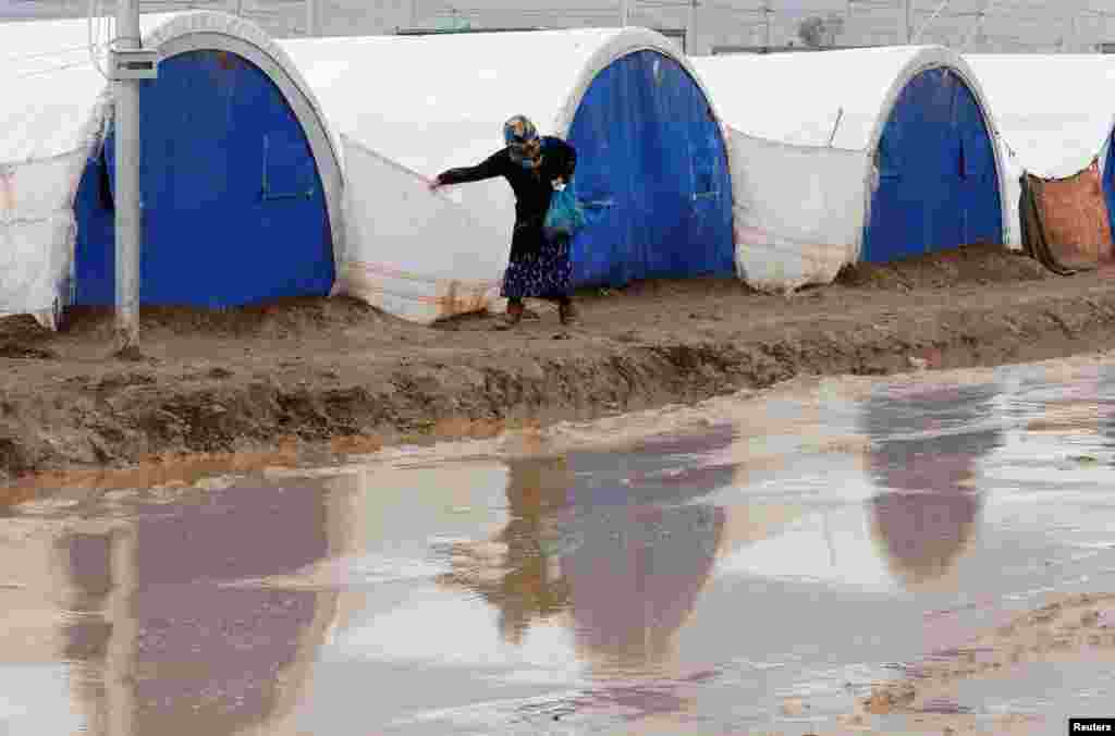 A displaced Iraqi woman who fled the Islamic State stronghold of Mosul walks following heavy rain at Khazer camp. (Reuters/Ammar Awad)