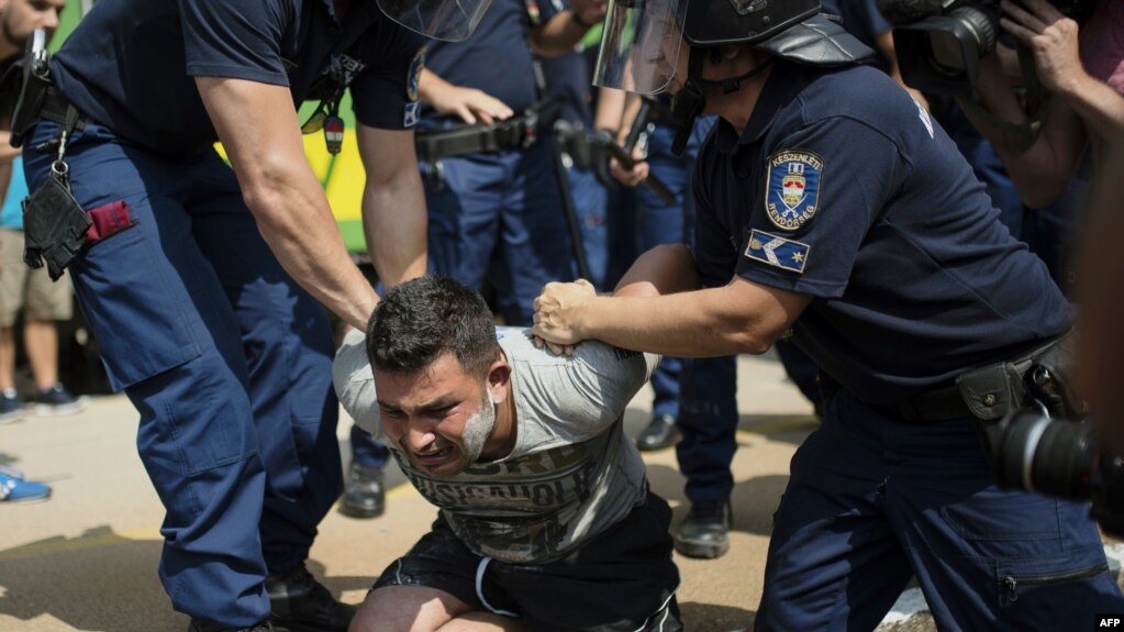 A migrant is arrested by Hungarian police after the train he was traveling on had been stopped. The treatment of migrants was one of the issues touched upon in a new Amnesty International report on human rights around the world that has criticized "a toxic agenda that hounds, scapegoats, and dehumanizes entire groups of people." (file photo)