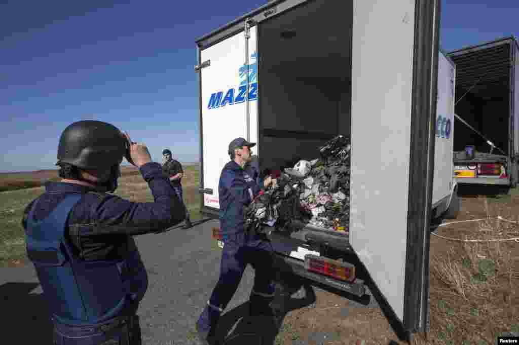 A member of Ukraine's Emergencies Ministry loads items recovered at the site where the downed Malaysia Airlines Flight MH17 crashed, near the village of Hrabove. Four Dutch police experts visited the crash site to help recover belongings and human remains despite fighting nearby. (Reuters/Shamil Zhumatov)