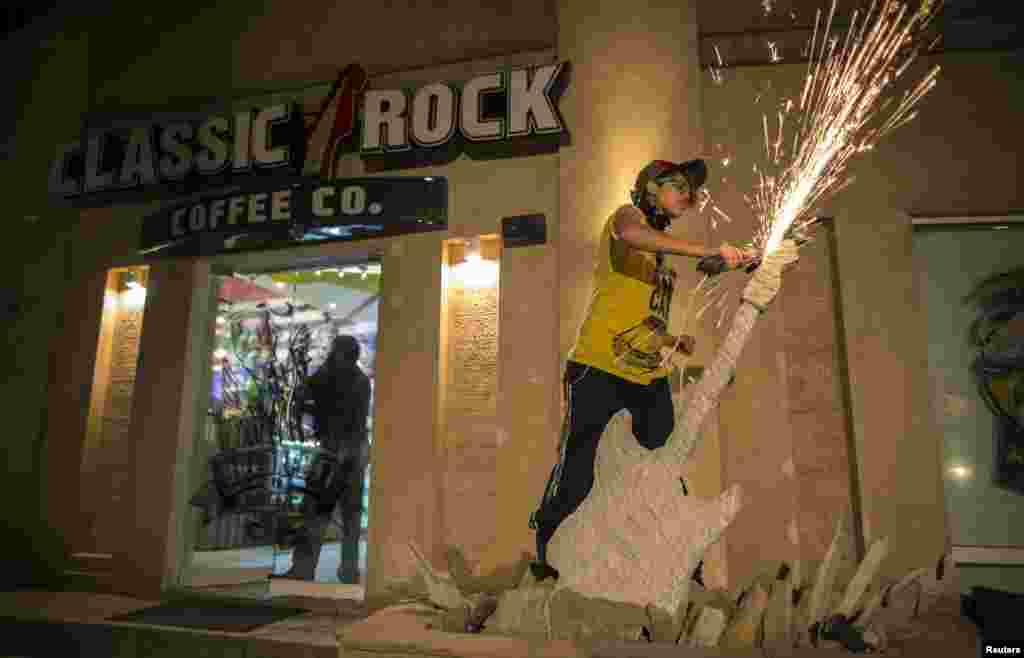 Afridi uses a circular saw as she sculpts a stone guitar outside Classic Rock Coffee.