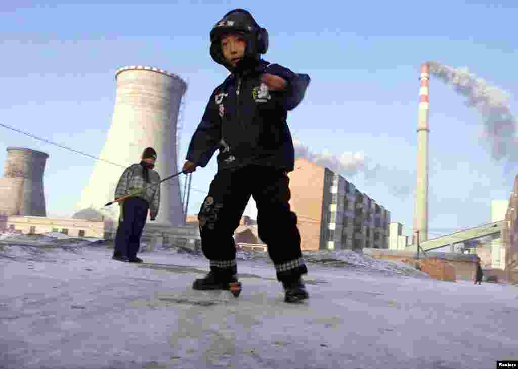 Boys spin tops in front of a coal-powered electricity plant in Xilinhot, Inner Mongolia, China.