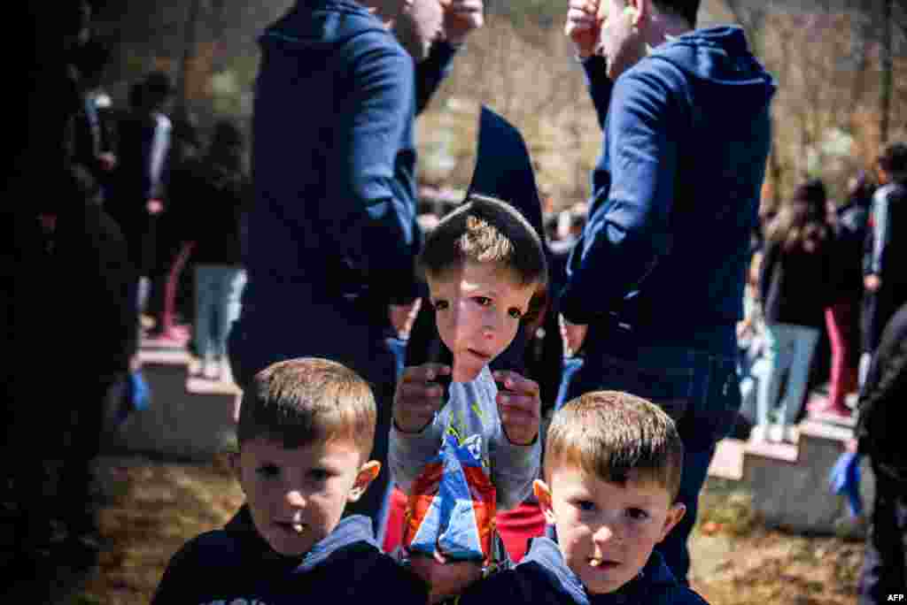 Ethnic Albanian children are reflected in a memorial dedicated to people killed during the Kosovo war, during a ceremony marking the 18th anniversary of the massacre in the village of Izbica on March 28. (AFP/Armend Nimani)