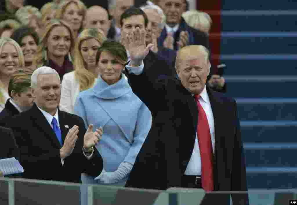 U.S. -- Vice-president elect Mike Pence (L) applauds as President-elect Donald Trump waves to the crowd as he arrives on the platform at the US Capitol in Washington, DC, on January 20, 2017,