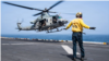 A US sailor directs the takeoff of a utility helicopter from the flight deck of the USS Boxer, an amphibious assault ship in the Arabian Sea enforcing Washington's blockade against Iran.