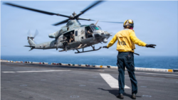 A US sailor directs the takeoff of a utility helicopter from the flight deck of the USS Boxer, an amphibious assault ship in the Arabian Sea enforcing Washington's blockade against Iran.