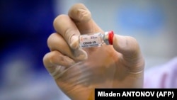 A lab technician holds a dose of a COVID-19 vaccine candidate ready for trial on monkeys at the National Primate Research Center of Thailand at Chulalongkorn University in Saraburi.