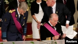 King Albert II (right) of Belgium, watched by his son Crown Prince Philippe (left), puts away his pen after signing an act of abdication during a ceremony at the Royal Palace on Belgian National Day in Brussels on July 21.