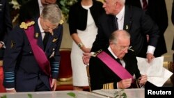 King Albert II (right) of Belgium, watched by his son Crown Prince Philippe (left), puts away his pen after signing an act of abdication during a ceremony at the Royal Palace on Belgian National Day in Brussels on July 21.