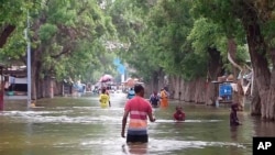 Banorët ecin nëpër rrugën e vërshuar si pasojë e shirave të mëdha, qyteti Beledweyne, Somali, 19 nëntor 2023.