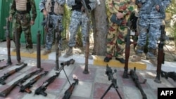 جنود عراقيون يعرضون أسلحة لعناصر جماعات مسلحة