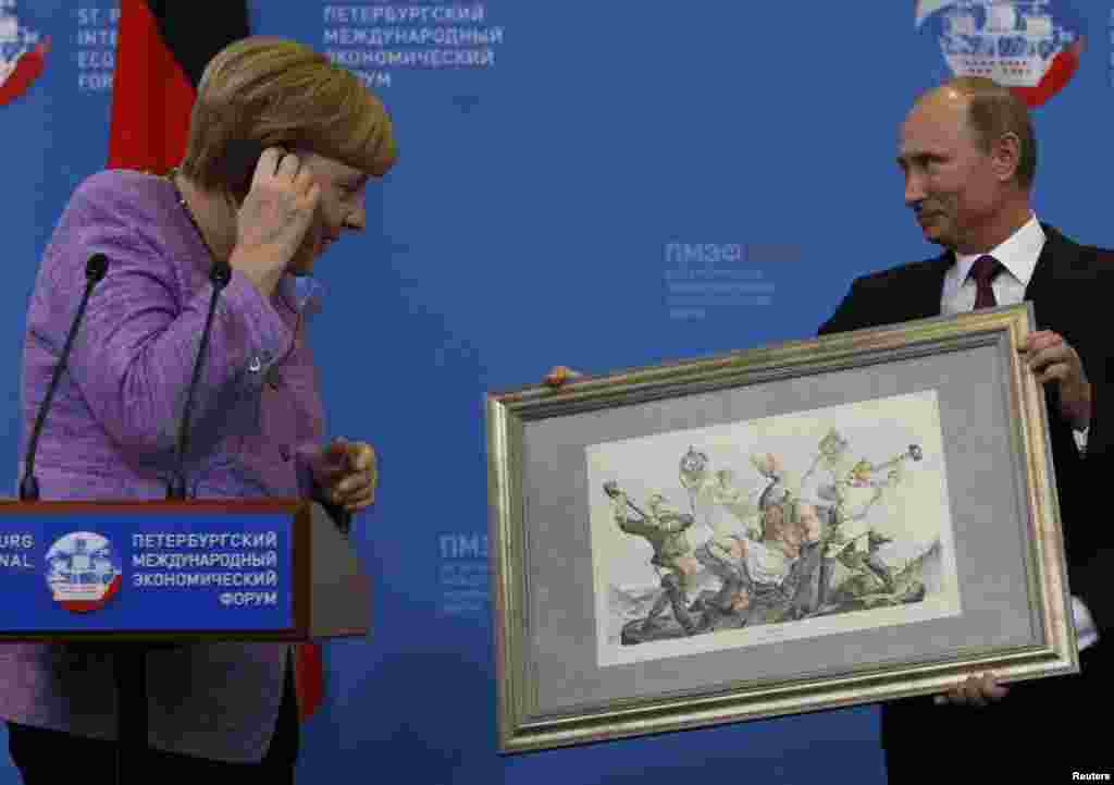 Președintele Rusiei, Vladimir Putin, oferă o litografie istorică Angelei Merkel, cancelara Germaniei, după întîlnirea lor cu ocazia Forumului Economic de la St. Petersburg. 