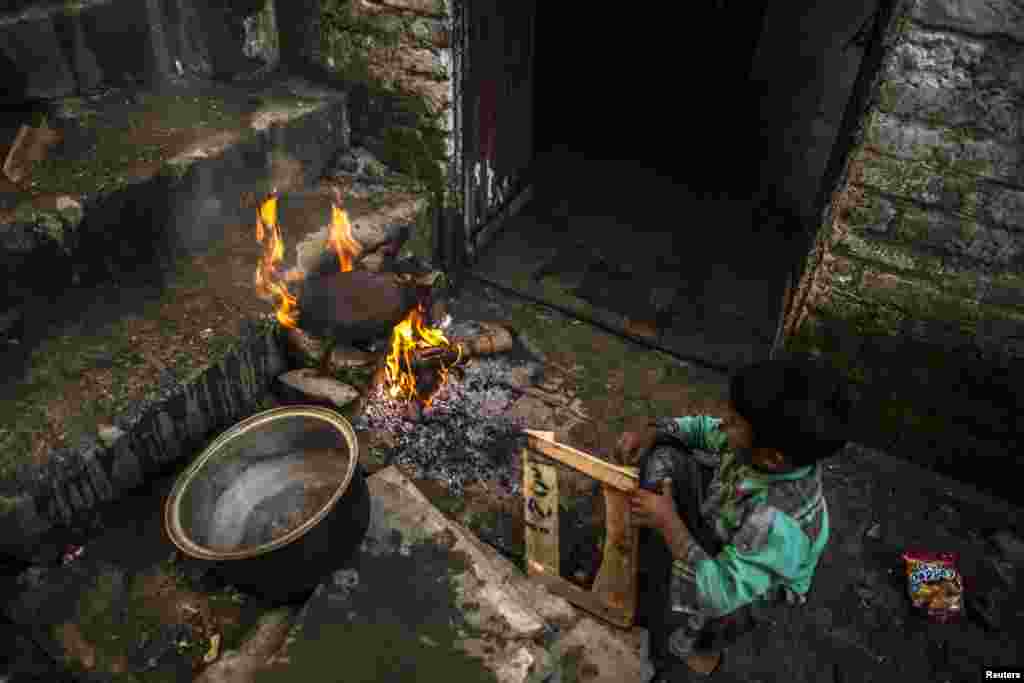 A boy plays near a wood-burning fire outside his house in a slum of Islamabad, Pakistan. (Reuters/Zohra Bensemra)