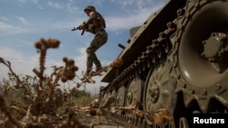 A Ukrainian soldier jumps from a military vehicle near a front line position in the Mykolayiv region on August 10.