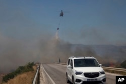 Një helikopter hedh ujë për të shuar një zjarr në Çesme, pranë Izmirit, Turqi, të enjten, 3 korrik 2025.