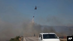 Helikopter ispušta vodu kako bi ugasio požar u Češmeu, blizu Izmira, Turska, u četvrtak, 3. jula 2025. godine.