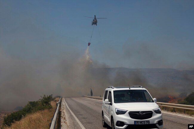 Një helikopter hedh ujë për të shuar një zjarr në Çesme, pranë Izmirit, Turqi, të enjten, 3 korrik 2025.