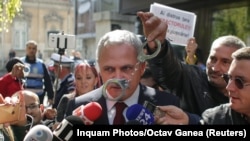 Un protestatar flutură o pereche de cătușe în fața liderului PSD Liviu Dragnea, condamnat definitiv într-un dosar penal, și cercetate în alte cîteva dosare penale, București, 3 octombrie 2017.