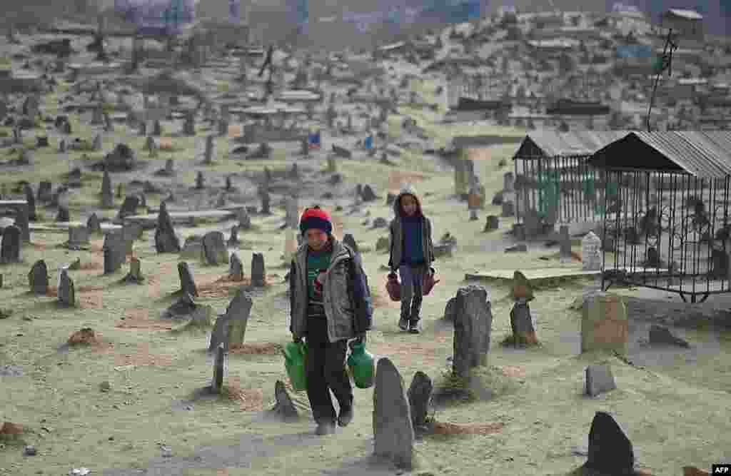 Afghan children who work as water vendors search for customers at the Kart-e Sakhi cemetery in Kabul. (AFP/Marai Shah)