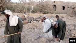 Men in the village in Farah Province search for their belongings after a U.S.-led air strike.