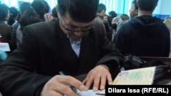 Мужчина заполняет документы на ярмарке вакансий в Шымкенте. 18 апреля 2015 года.