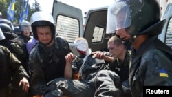 Киевские милиционеры выносят пострадавшего товарища во время столкновений у Верховной рады 31 августа 