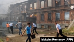 Police officers and municipal workers run with a hose as they attempt to extinguish a fire in Rostov-on-Don on August 21.