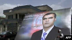 کارگر افغان هنگام عبور از سرک از مقابل تصویر یکی از کاندیدان انتخابات