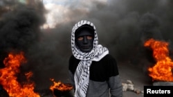 A Palestinian demonstrator stands near burning tires during clashes with Israeli troops at a protest against the U.S. decision to recognize Jerusalem as the capital of Israel, near the West Bank city of Nablus on December 15.