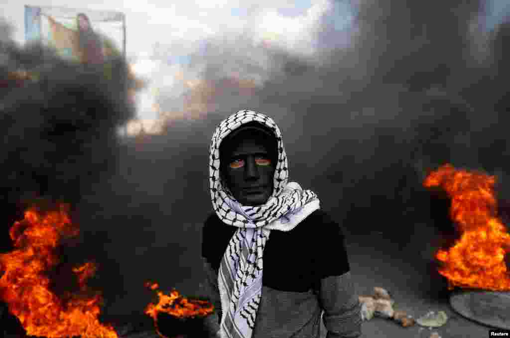 ЗАПАДЕН БРЕГ - Палестински демонстрант со маска фотографиран за време на најновите судири на Палестинците и израелските безбедносни сили во Западен Брег. Протестите, судирите, палењето јавен имот и пукањето не престануваат на територијата на цела Палестина по најавата на американскиот претседател Доналд Трамп за признавање на Ерусалим за главен град на Израел.